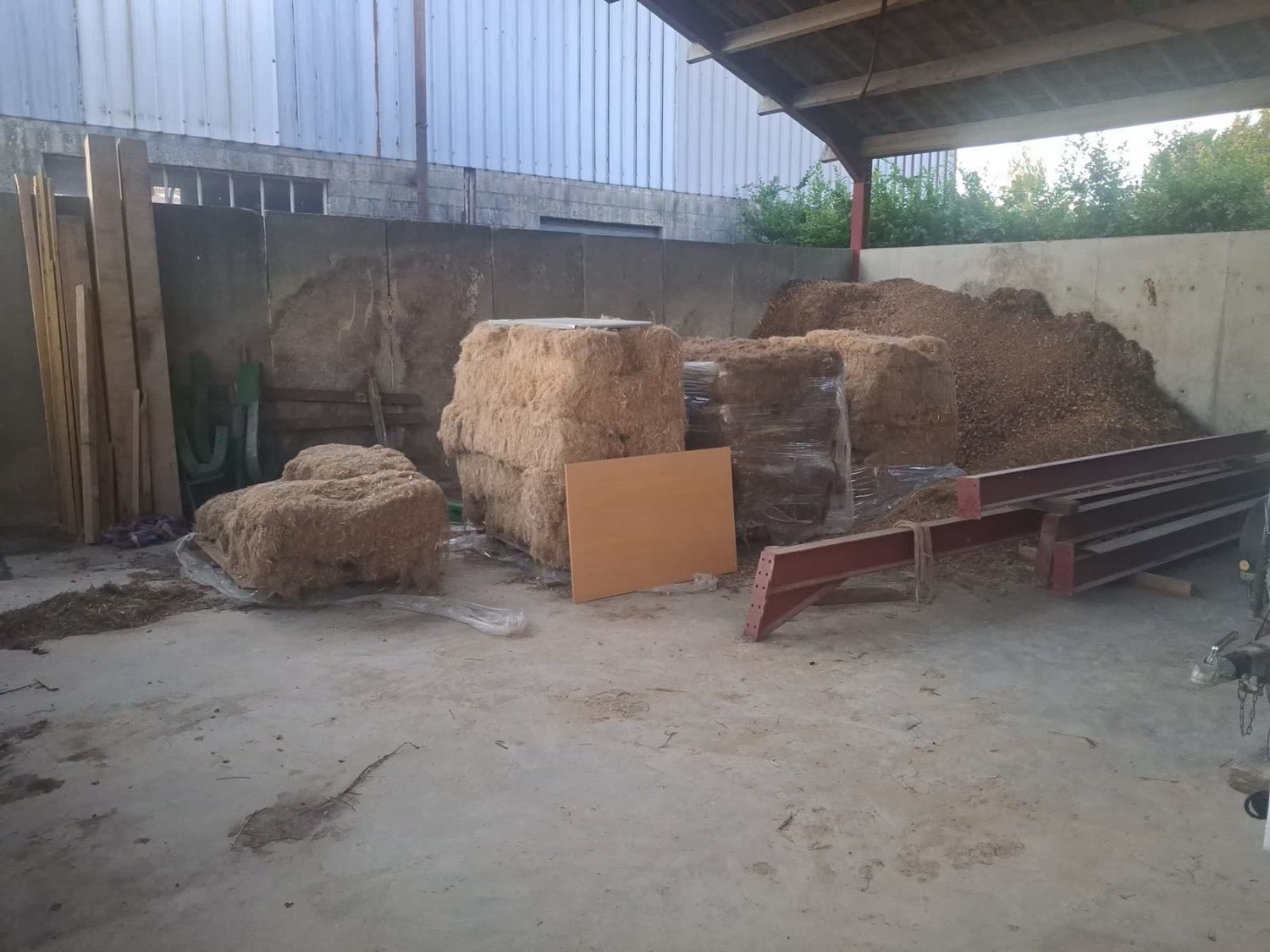 Bois, plaquettes et fourrage stockés dans un bâtiment agricole avant séchage